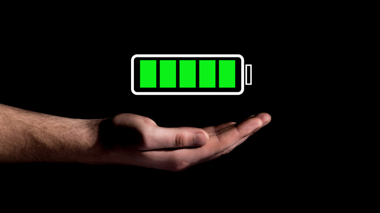 hand showing battery charge icon on black background