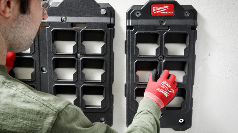 A person installing Packout's Large Wall Plate on a wall.