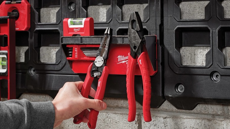 Person putting hand tools on Packout magnetic rack.