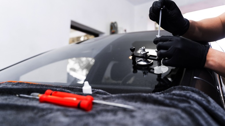 A technician repairing a windshield crack using a tool