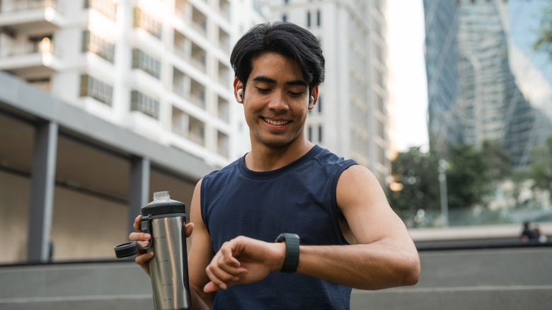 man on run checks apple watch wearing airpods