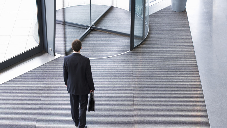 Business man walks toward revolving door