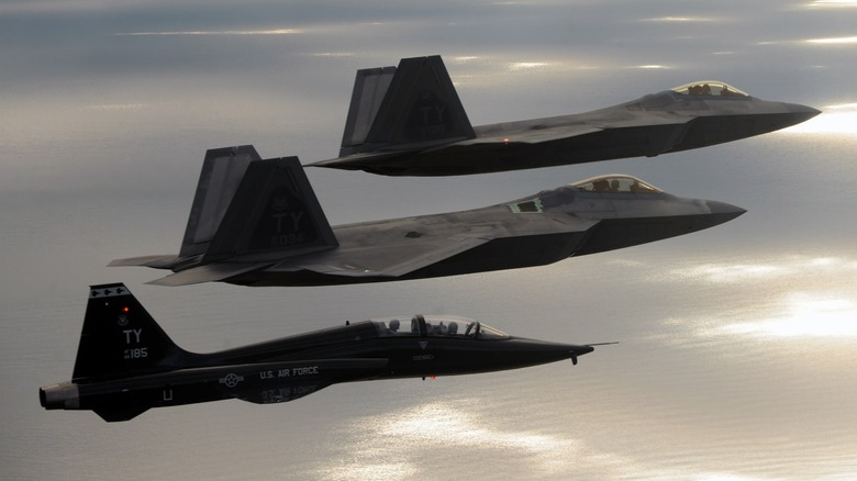 Two U.S. Air Force F-22s flying alongside a T-28 Talon trainer
