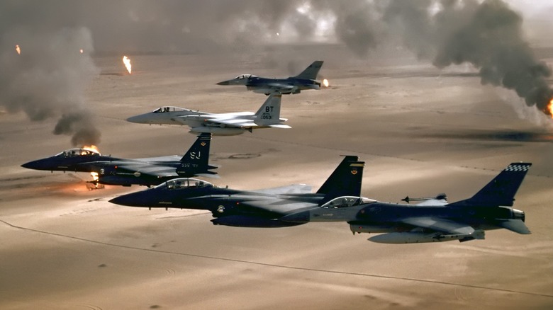 A squadron of F-16s and F-15s flying over burning oil fields during Operation Desert Storm in 1991.
