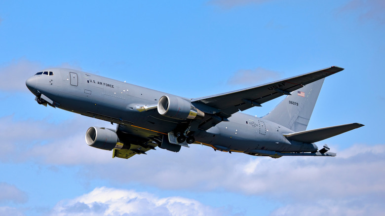 Ground view of US Air Force KC-46 Pegasus tanker taking off under blue skies.