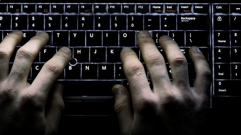 Two hands at a backlit keyboard
