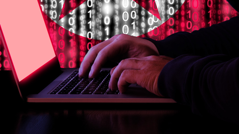 North Korea flag behind hands at keyboard