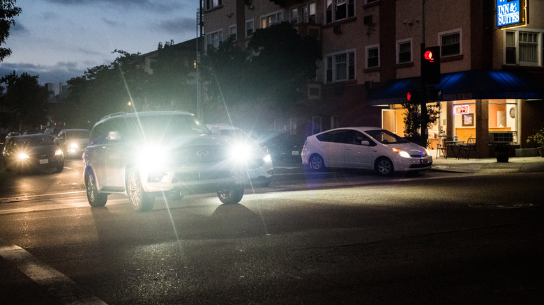 A vehicle on an urban street at night with bright LED headlights