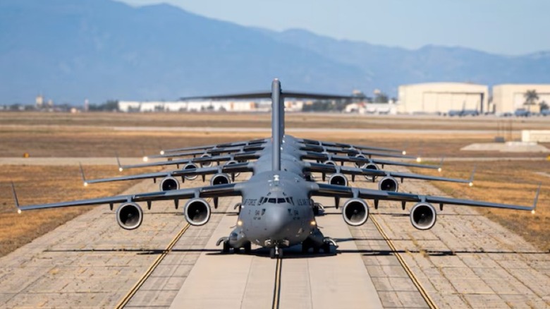 A line of C-17 Globemaster II aircraft taxi on a runway in California.