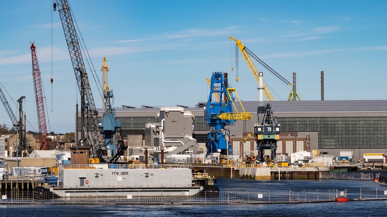 US Navy shipyard with cranes and a massive building