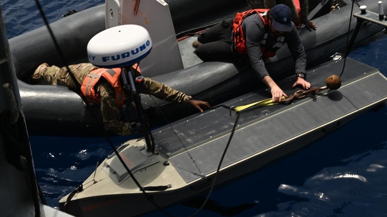 Two people in an inflatable boat launching the Lightfish drone at sea