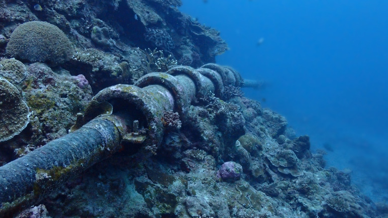 An undersea pipeline lying on the seafloor with signs of corrosion and damage.
