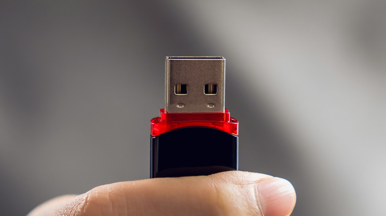 A person holding a USB flash drive.