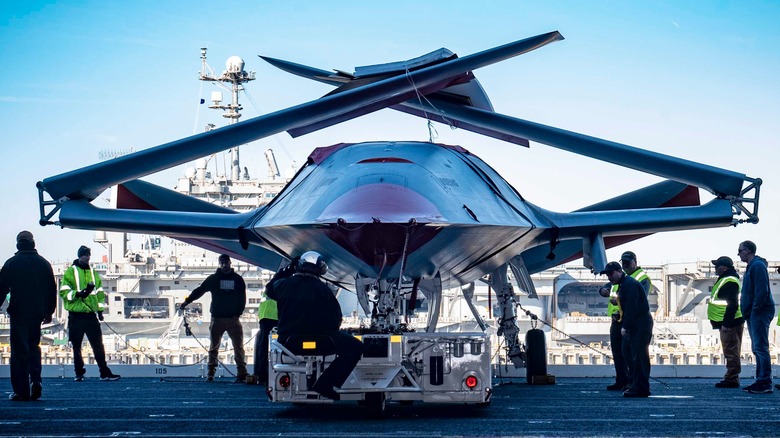 An MQ-25 moving into the USS George H.W. Bush's hangar surrounded by Navy personnel