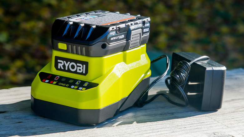A Ryobi battery on its charger outside.
