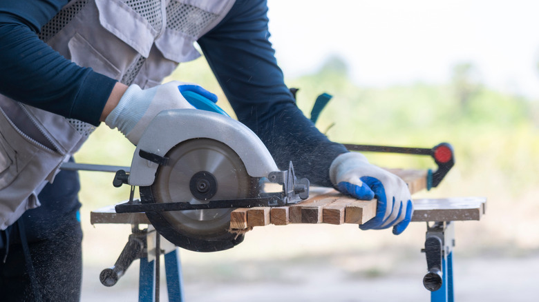 Person cutting through multiple wood stakes with circular saw
