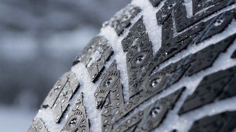Close shot of tread of studded winter tire with snow in tread grooves