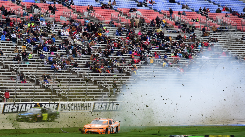An empty crowd watches a NASCAR Chevrolet crash onto the grass at Texas Motor Speedway.