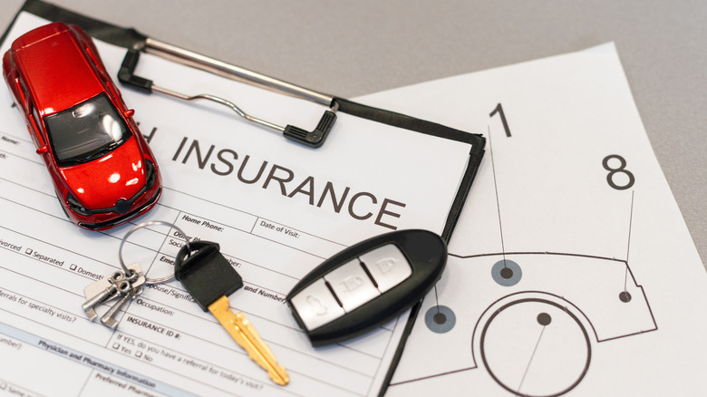 Car insurance forms with red toy vehicle and car keys