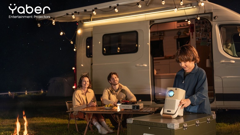 Family setting up Yaber projector in front of camper