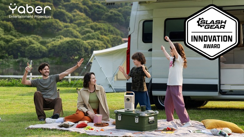 Family having picnic outside camper with Yaber projector set up