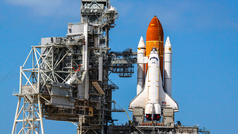 Space Shuttle on the launch pad with fuel tank and solid-rocket boosters attached.