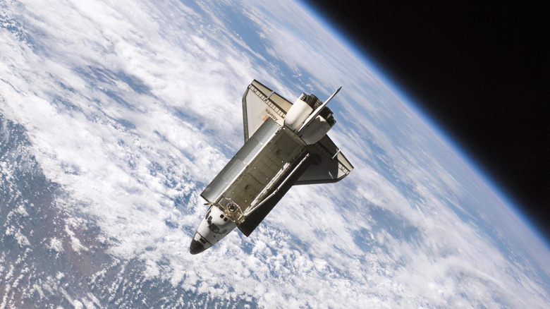 Space Shuttle Atlantis pictured in orbit after undocking from the ISS with the earth prominent in the background.