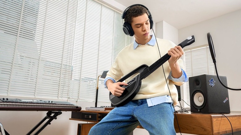 A man with headphones plays the LiberLive smart guitar