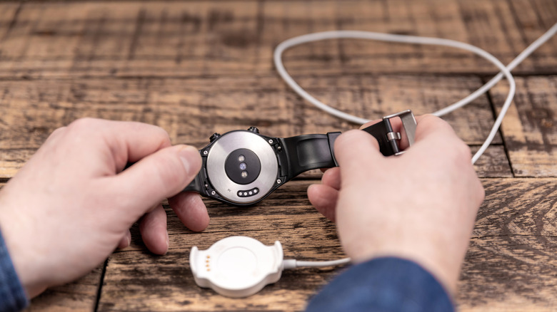 Person connecting a smartwatch to a charger