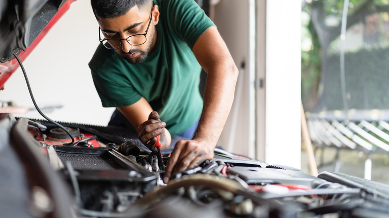 Mechanic servicing a car in a home garage