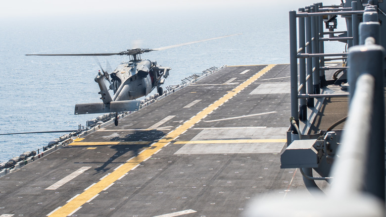 Rear view of helicopter landing on deck of USS Essex amphibious assault ship.