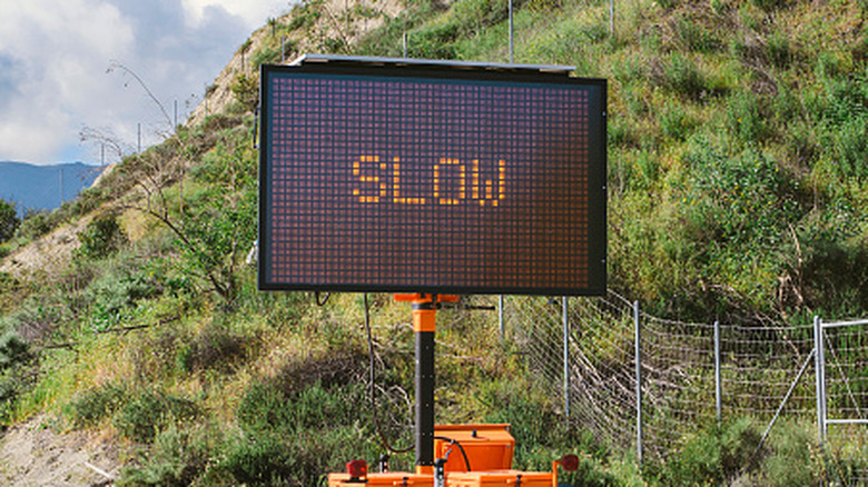 A digital road sign telling drivers to drive slow.