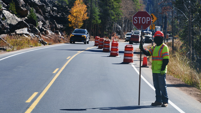 Road construction site narrowed down to one lane with worker holding stop sign