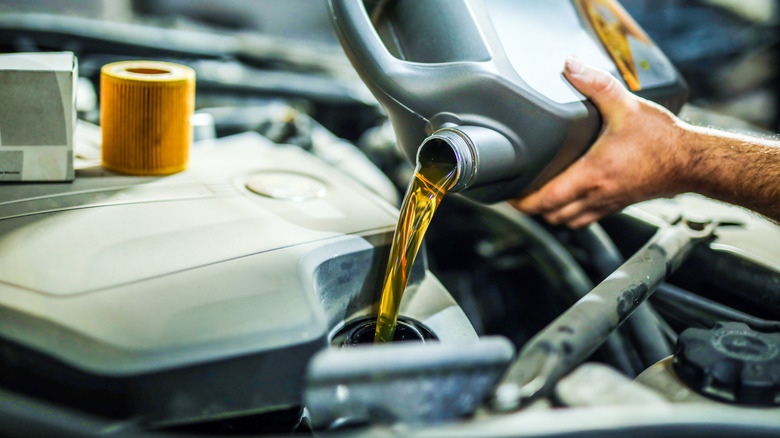 Close-up of person pouring engine oil into a car engine.