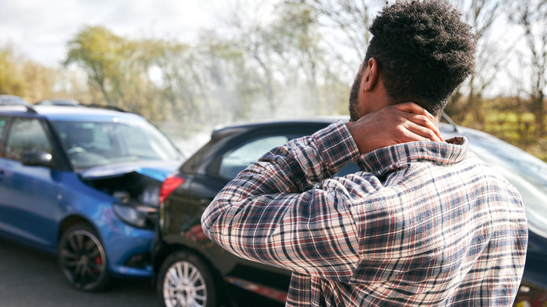 Driver stands before two damaged cars