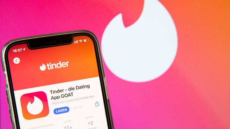 Aplicativo Tinder em um iPhone e logotipo em segundo plano