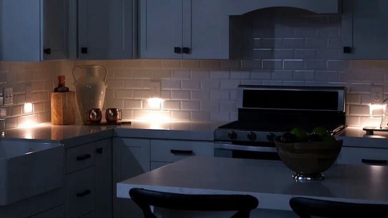 Three SnapPower Guidelight 2-LED Outlet Covers in a dark kitchen