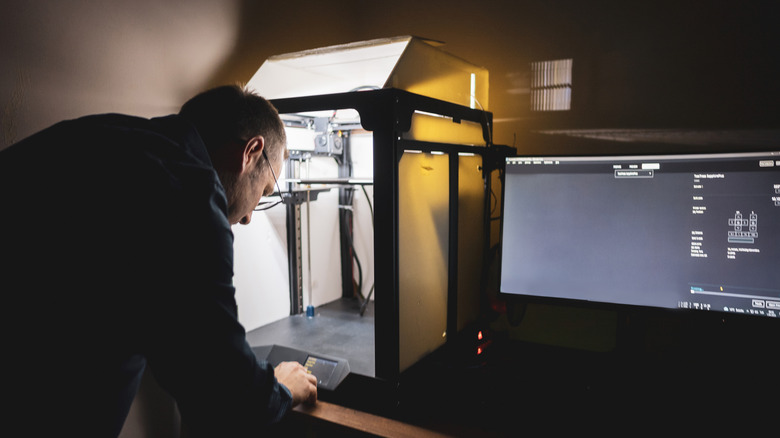 Man programming 3D printer.