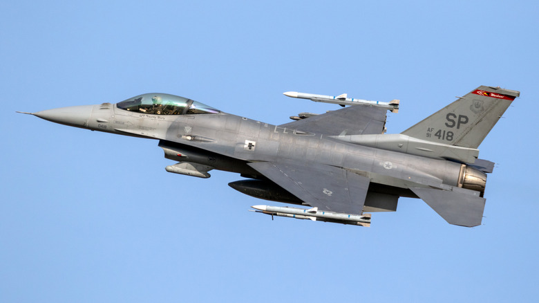 An F-16 jet flying against a blue sky.