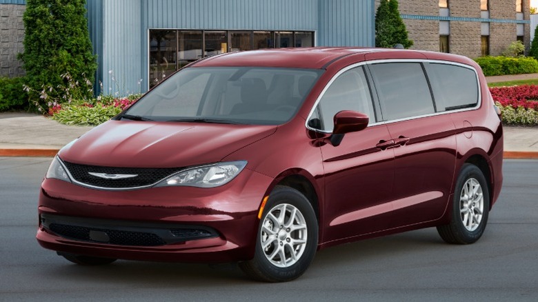 Red Chrysler Voyager in a parking lot in front of a building