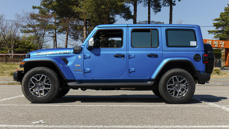 Side view of blue Jeep Wrangler 4xe parked in parking lot.