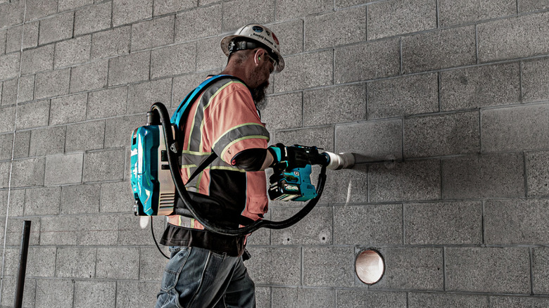 Person using a Makita 40V backpack dry dust extractor on job site