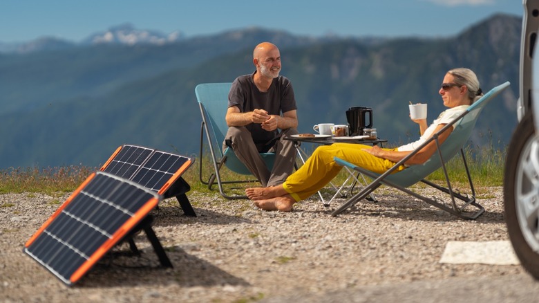 man and women sitting behind solar panels