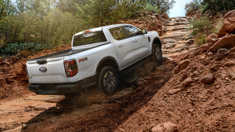 Rear view of white Ford Ranger FX4 climbing up off-road trail.