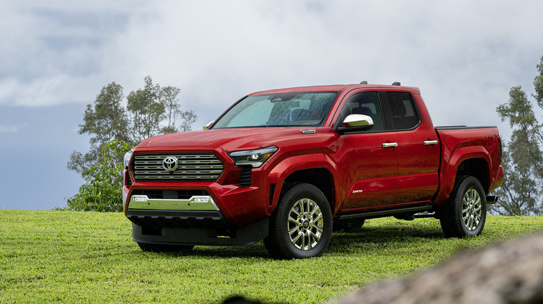 Front 3/4 view of red Toyota Tacoma hybrid parked on hilltop.