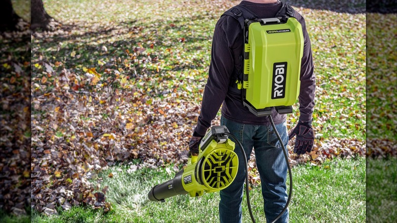 Person using Ryobi leaf blower connected to 40V Backpack Power Supply/Charger