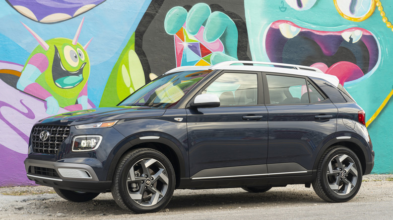 Front 3/4 view of Hyundai Venue parked on dirt in front of mural