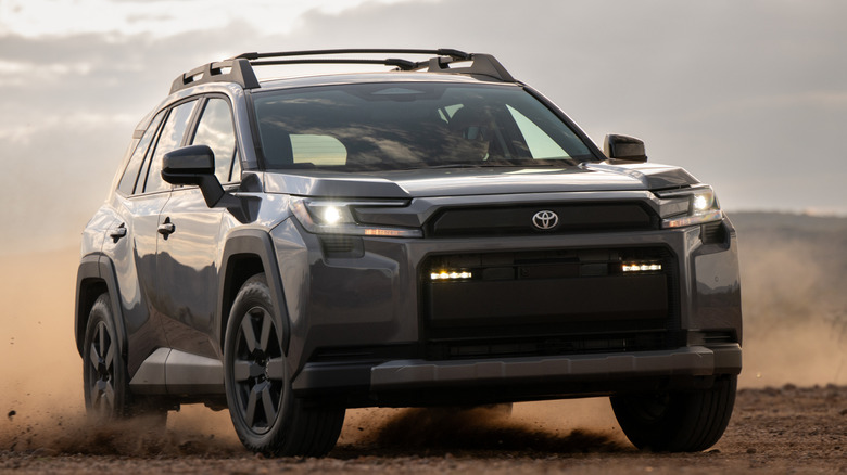 Front 3/4 view of Toyota RAV4 driving in the dirt and kicking up dust
