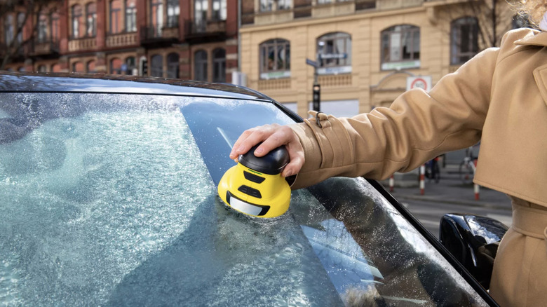 Perosn using an electric ice scraper