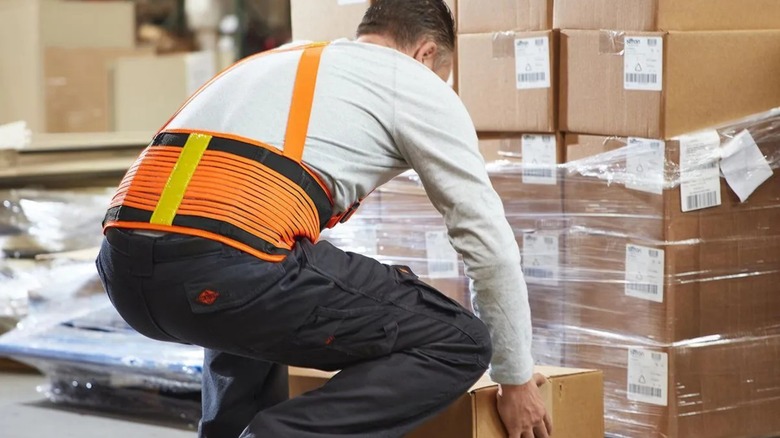 Worker lifting boxes while wearing Western Safety Back Support Belt with Reflector